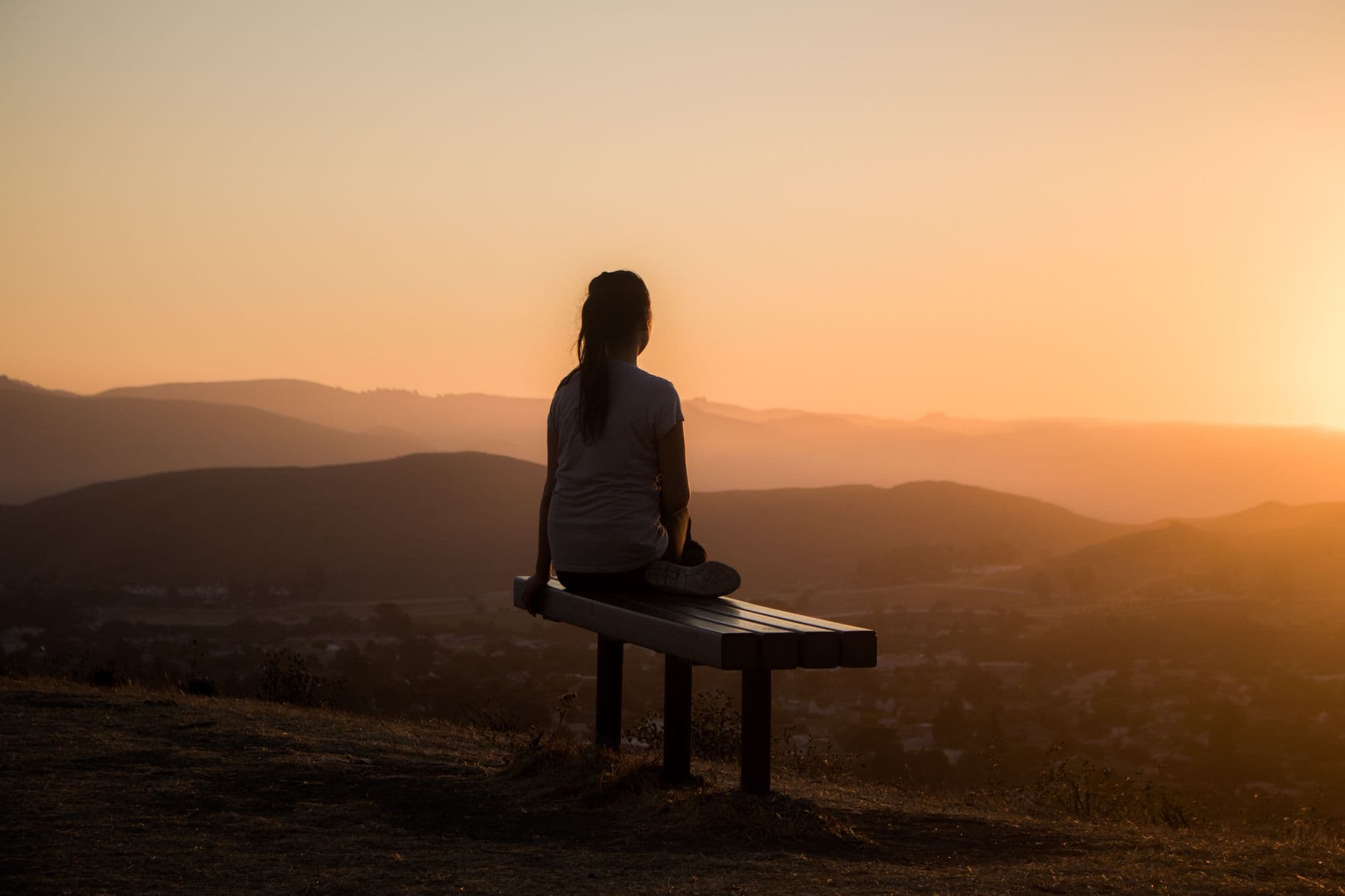 Girl on a bench watching the sunset
