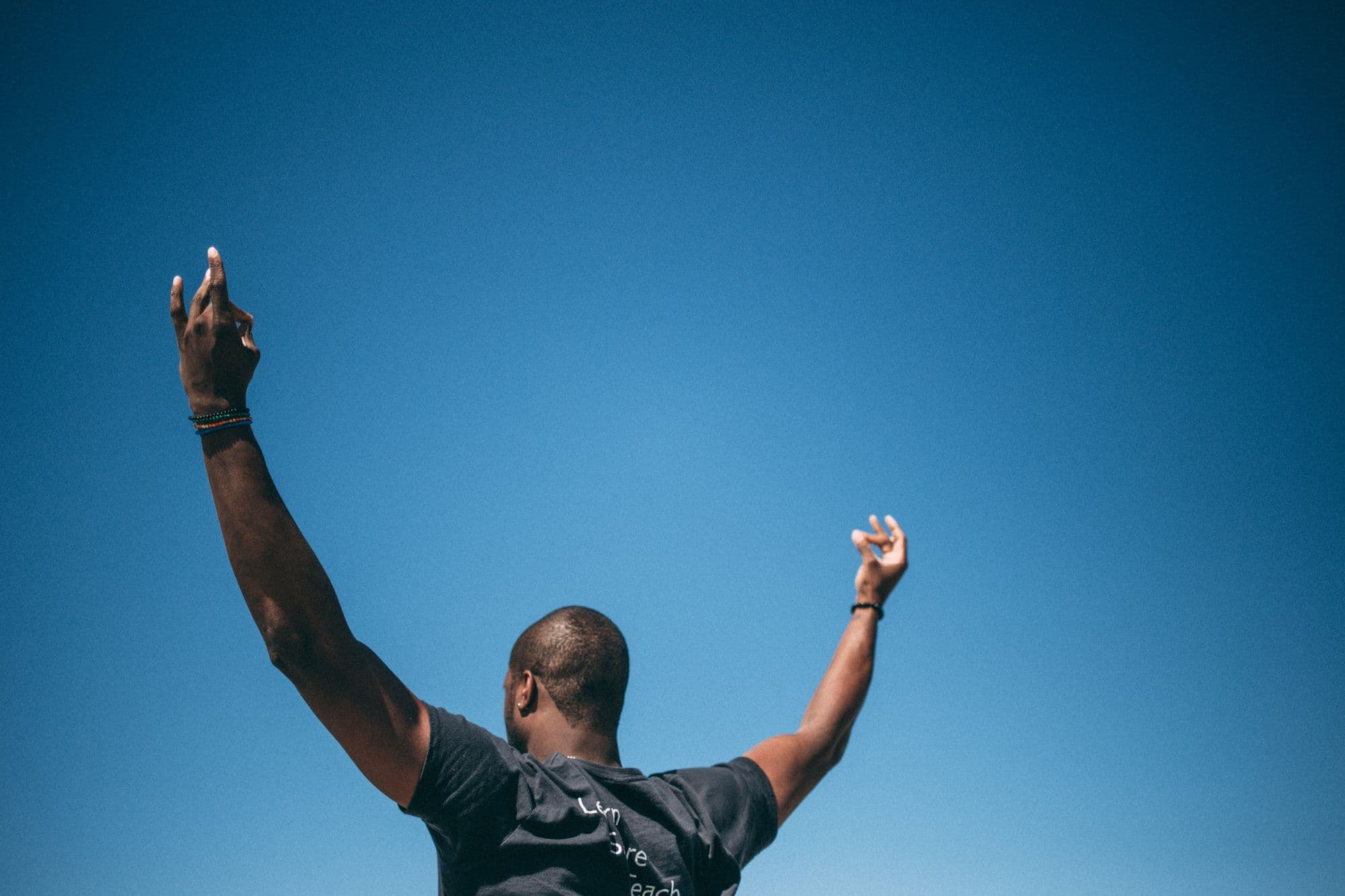 man from back, raised hands in prayer