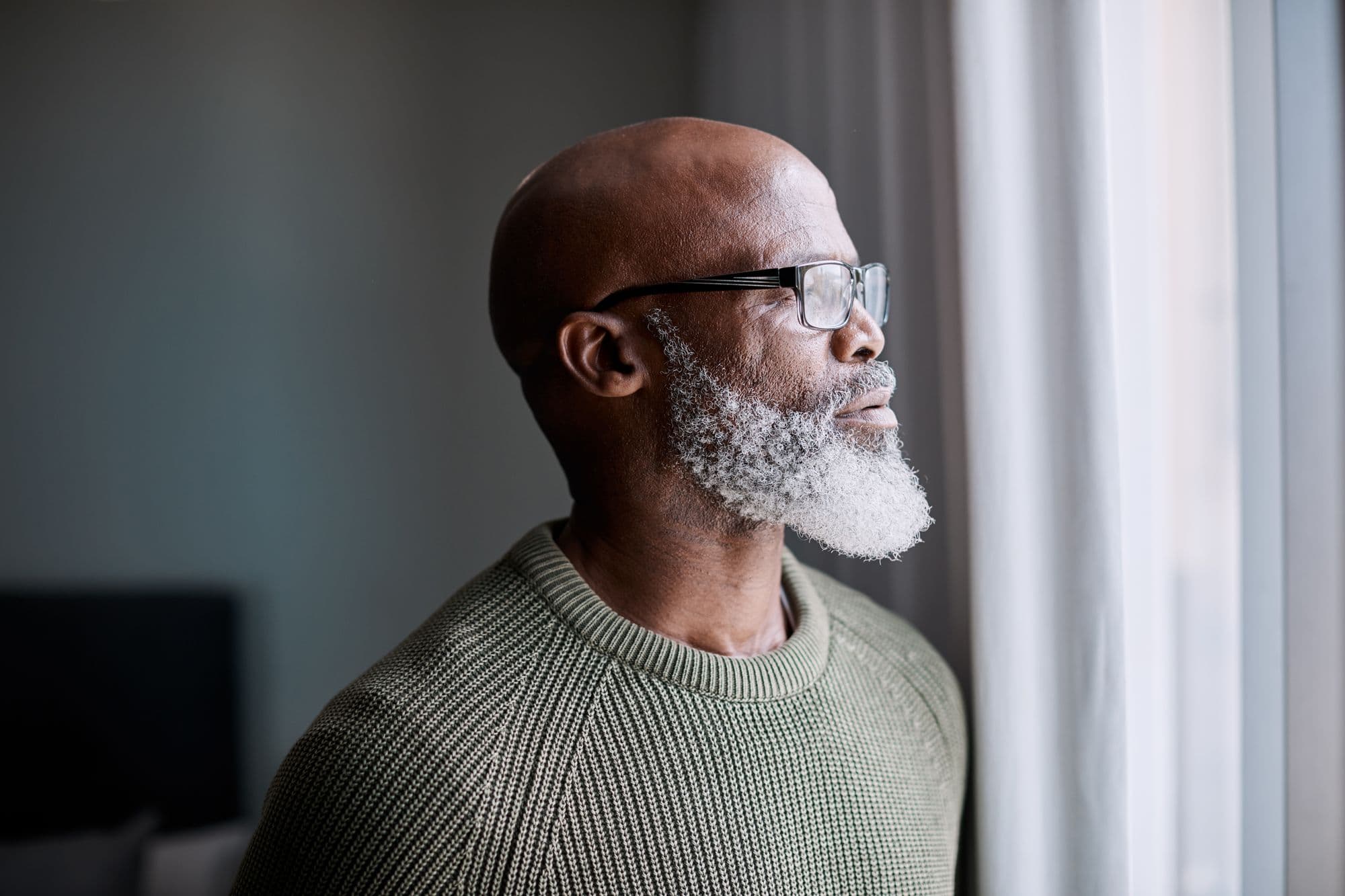 Man with beard looking through a window