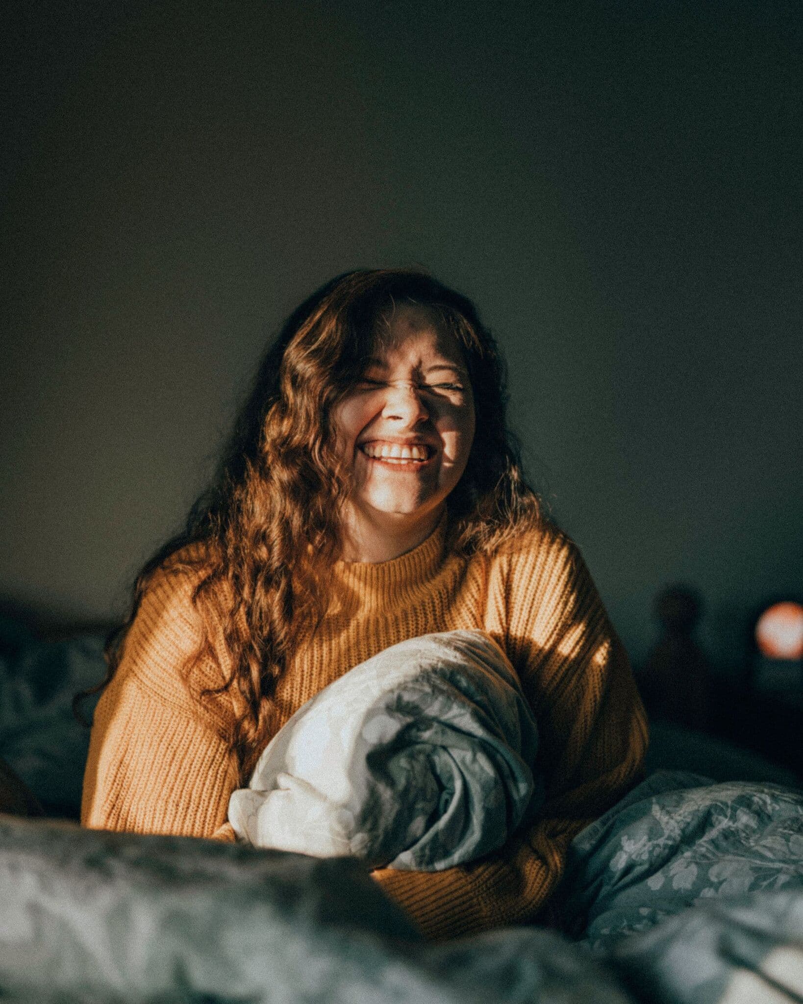 woman laughing in bed