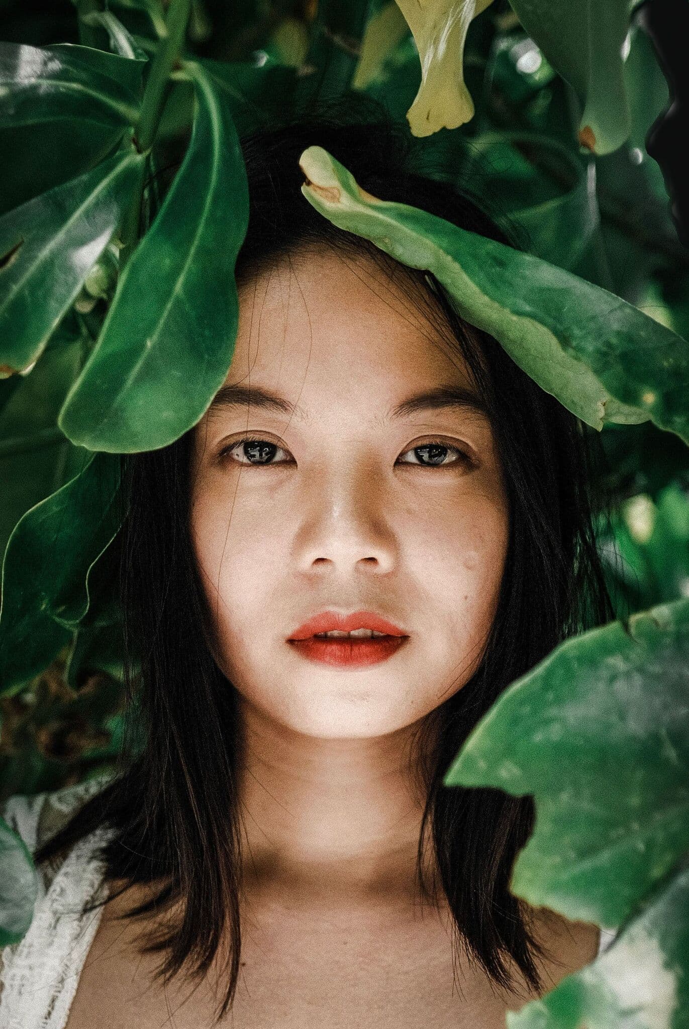 woman smiling behind leaves