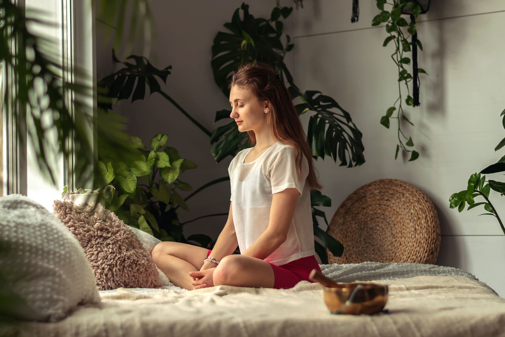 Young attractive woman practices yoga at home,sitting cross-legged.Yoga mudra.Relaxation and meditation.Wellness,wellbeing,mental health concept.